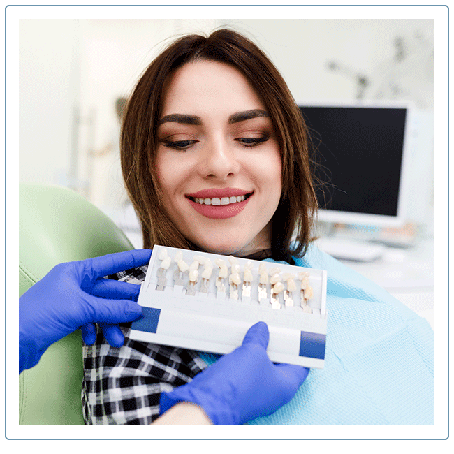 dentist holding a sample of porcelain veneer options for a female client