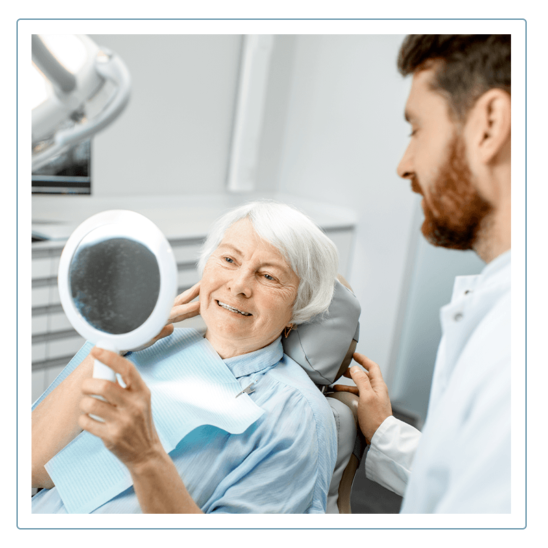 woman holding a mirror and examining her new smile