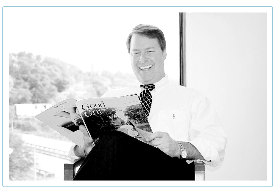 man in a suit and tie reading a magazine