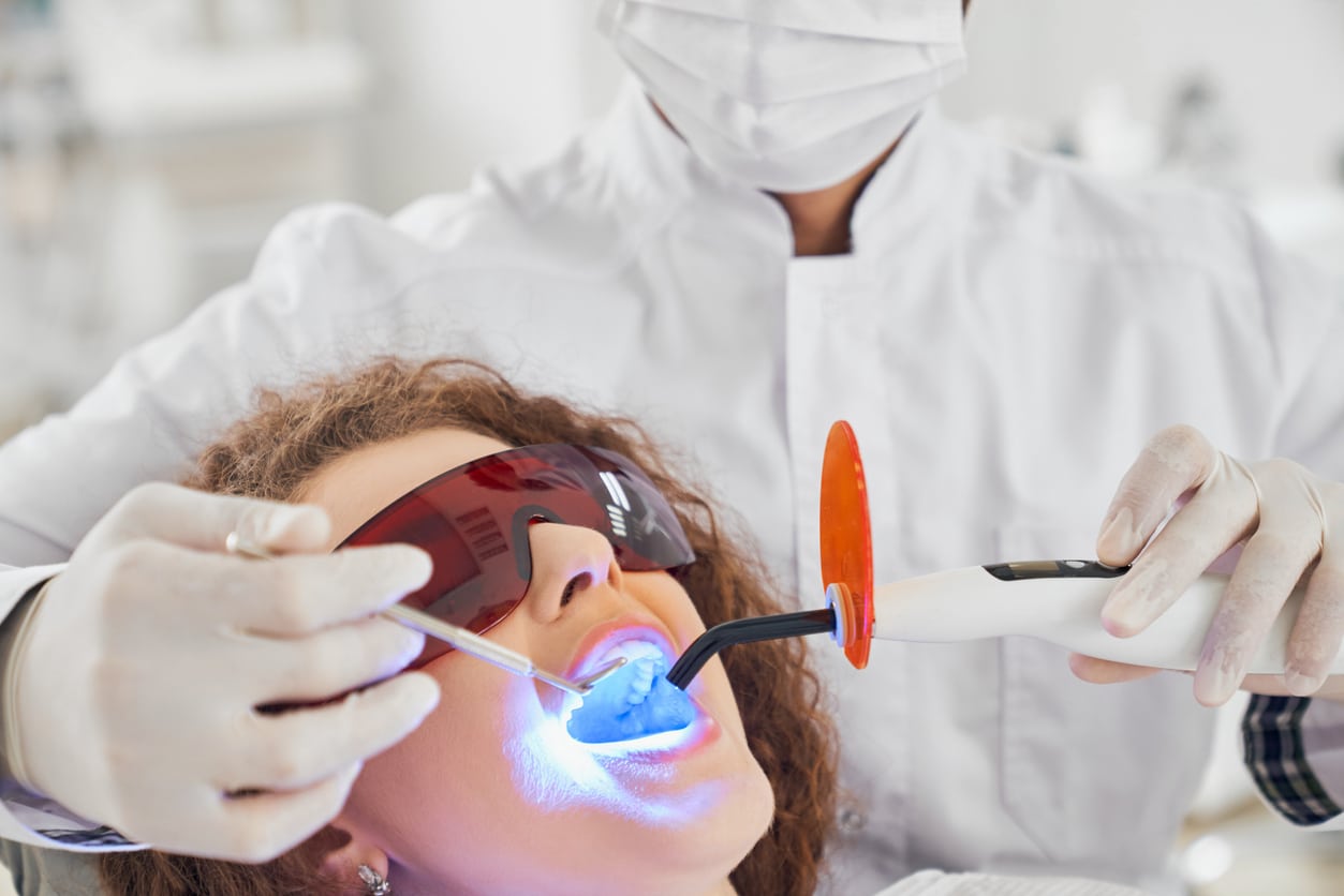 A woman with dark curly hair undergoing laser dentistry treatments.