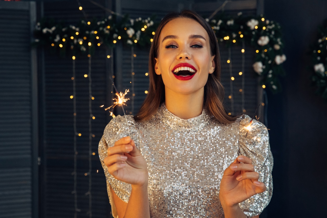 Happy woman holding a festive sparkler on Christmas night.