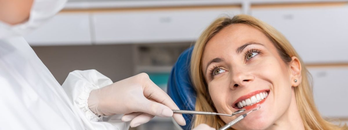 A woman admires her new TeethXpress dental implants in the dentist’s office.
