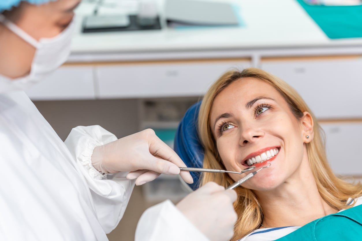 A woman admires her new TeethXpress dental implants in the dentist’s office.