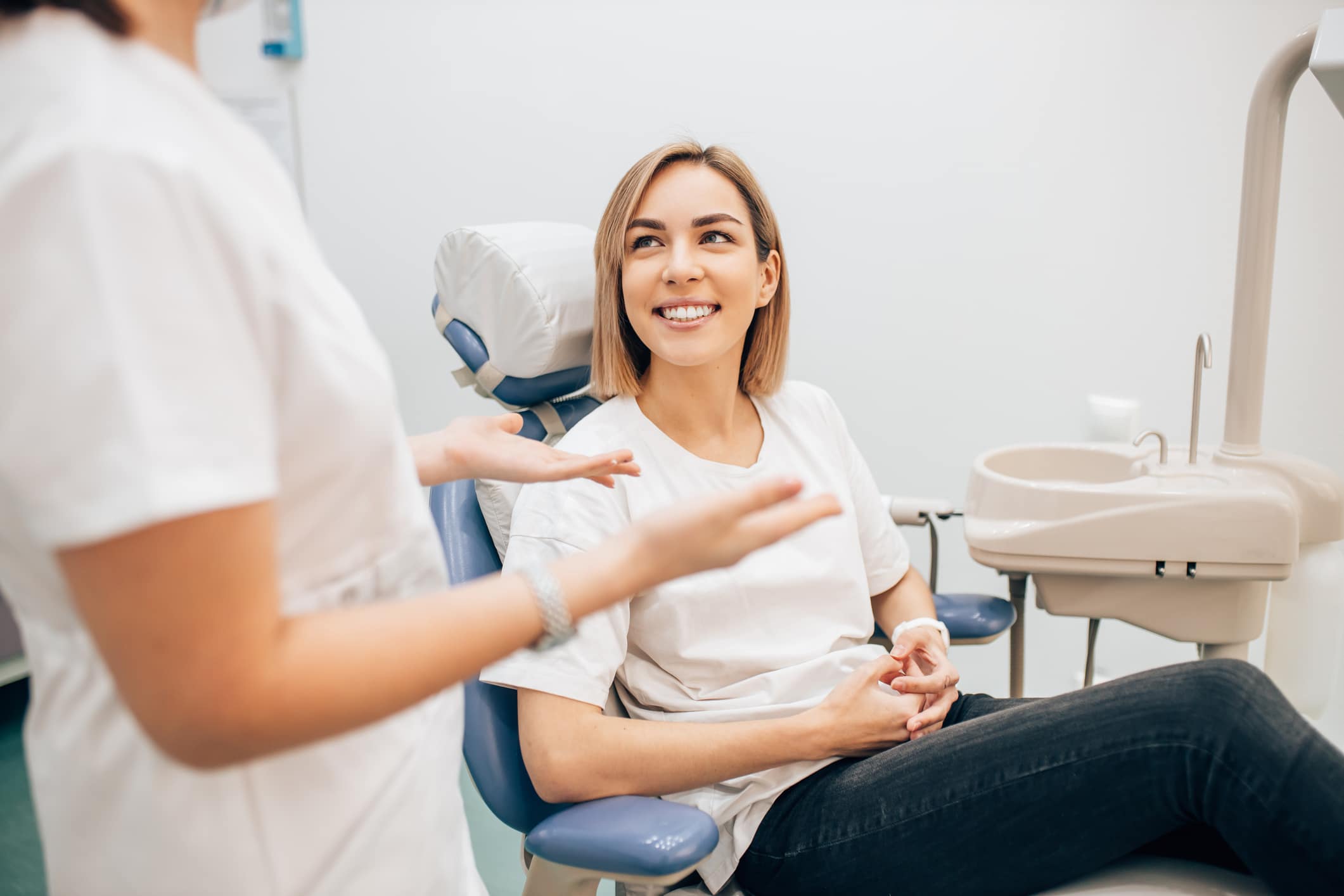 A woman seated in a dental chair speaks with her dentist about managing dental anxiety.