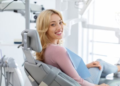 A woman sits in a dental chair smiling confidently during a cosmetic dentistry smile makeover consultation in Birmingham, AL.