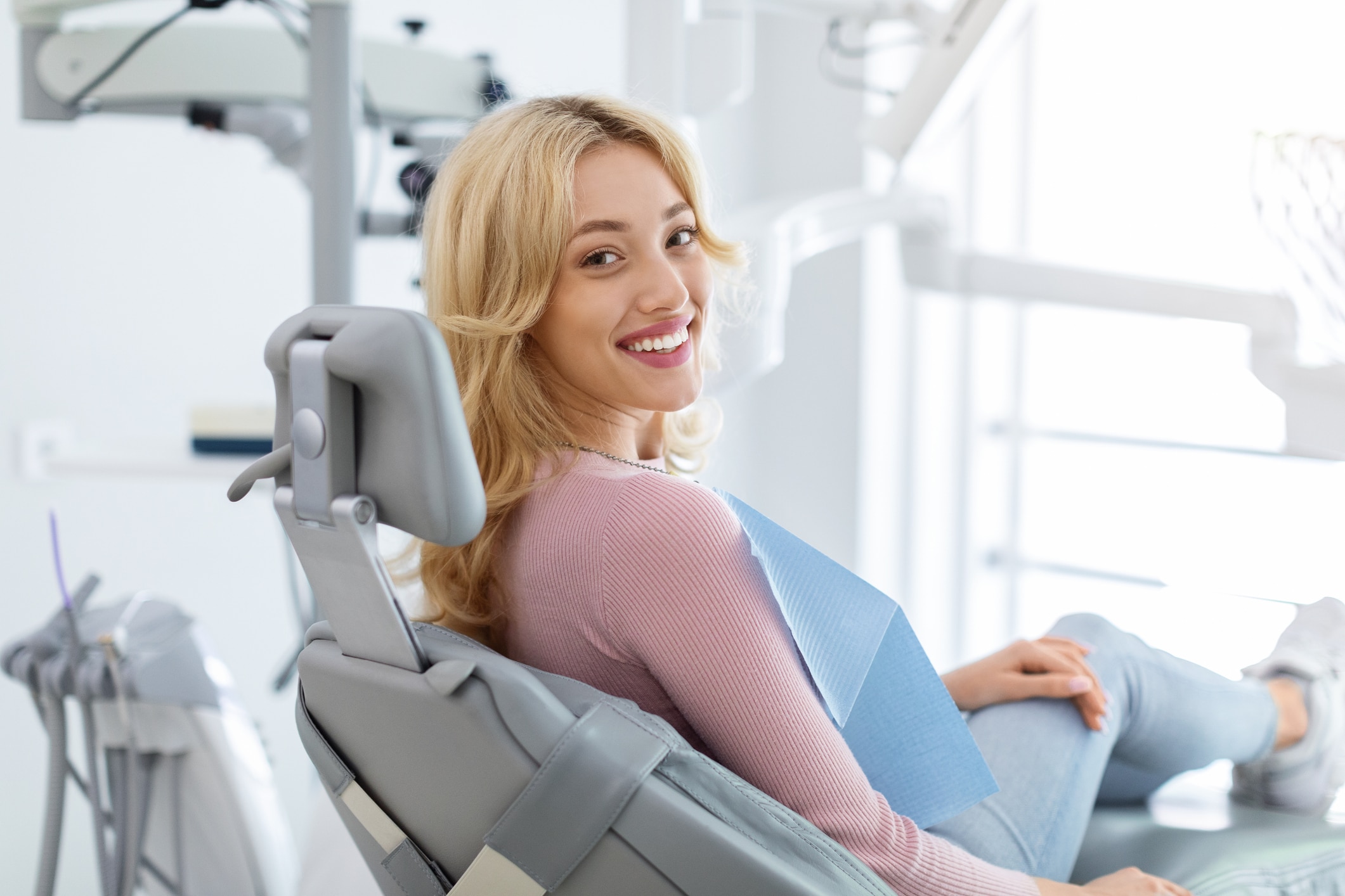 A woman sits in a dental chair smiling confidently during a cosmetic dentistry smile makeover consultation in Birmingham, AL.